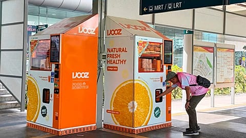 A man collects orange juice from IJooz vending machine in Singapore, 30 April, 2026