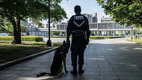 A member of the police and the K-9 unit stand guard near the Peace Park Memorial in Hiroshima, 21 May, 2023