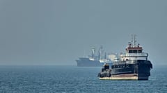 An Iranian tugboat floats in the foreground as cargo ships sit at anchor in the Strait of Hormuz off Bandar Abbas, 4 May, 2026