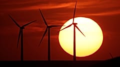 In this Aug. 23, 2013 file photo wind turbines are silhouetted by the setting sun as they produce electricity near Beaumont, Kan.