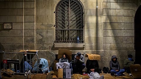 Una cola de migrantes esperan durante la noche, y bajo la lluvia, frente al Ayuntamiento de Barcelona para obtener la documentación necesaria para regularizarse