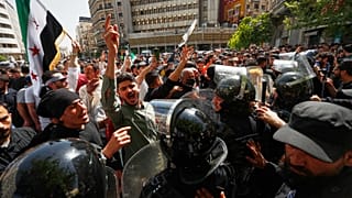 متظاهرون يرددون شعارات بجانب شرطة مكافحة الشغب السورية خلال احتجاج يدعو إلى تحسين الظروف المعيشية والخدمات العامة في ميدان يوسف العظمة في دمشق، سوريا، الجمعة 17 أبريل 2026.