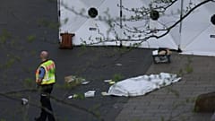 A policeman stands next to a body bag after a car crashed into several people in Leipzig, Germany, Monday, May 4, 2026