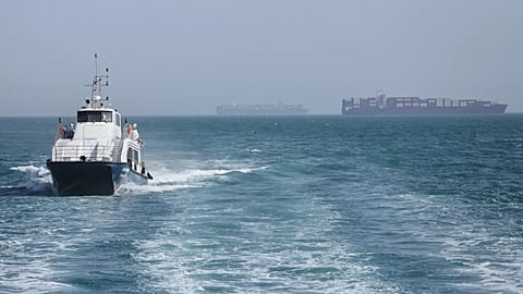 Um barco de patrulha move-se na água enquanto os navios de carga estão ancorados no Estreito de Ormuz, ao largo de Bandar Abbas, 2 de maio de 2026