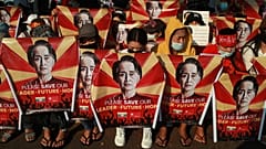 Anti-coup protesters hold posters with an image of Aung San Suu Kyi as they gather in Yangon, 20 February, 2021 