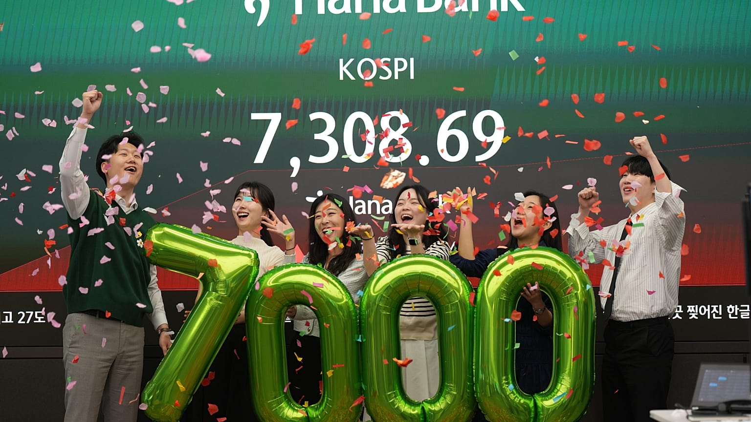 Des employés de Hana Bank posent pour célébrer le dépassement des 7 000 points de l’indice KOSPI, à Séoul, le 6 mai 2026.