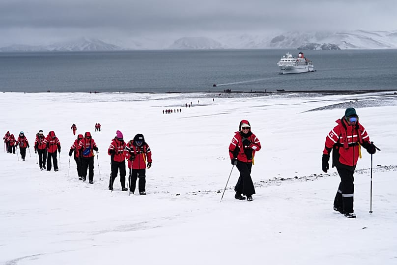Passengers walk inside the volcano at Deception Island in Antarctica, Wednesday, Nov. 26, 2025.