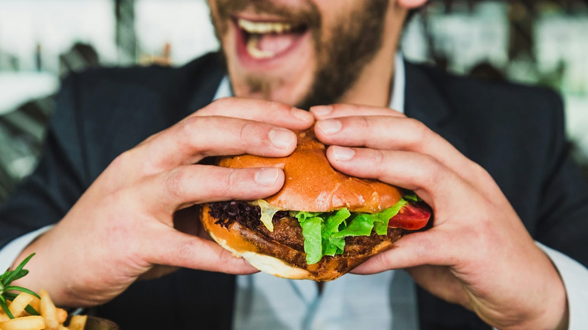 Ein Mann im Anzug isst einen Burger.