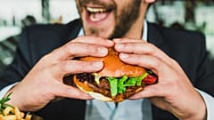 A man in a suit eating a burger. 