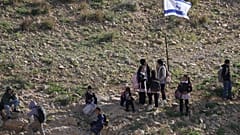 طلاب فلسطينيون يسيرون إلى المدرسة على طول سياج يفصل قريتهم عن مستوطنة الكرمل الإسرائيلية القريبة