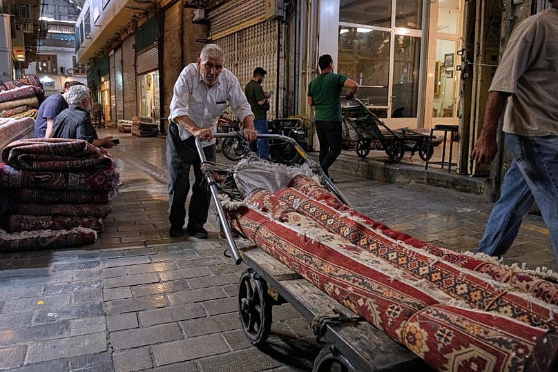 FILE: A man moves carpets at the historic Grand Bazaar, in Tehran, 3 May 2026