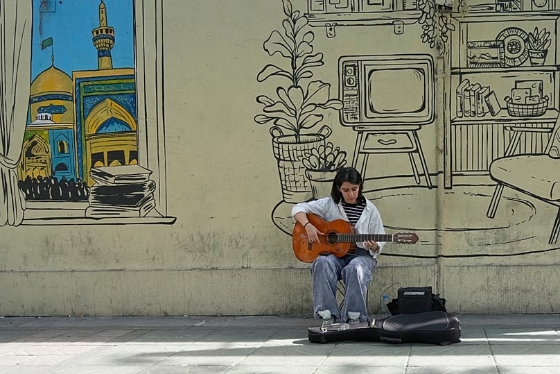 FILE: A street musician plays the guitar on Enqelab-e-Eslami street, in downtown Tehran, 25 April 2026