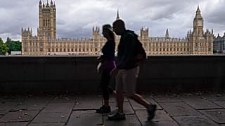 FILE. People walk on the south bank of the River Thames, backdropped by the Palace of Westminster in London, 22 Aug. 2022