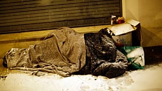 A homeless man sleeps during a snowfall in Issy les Moulineaux, west of Paris