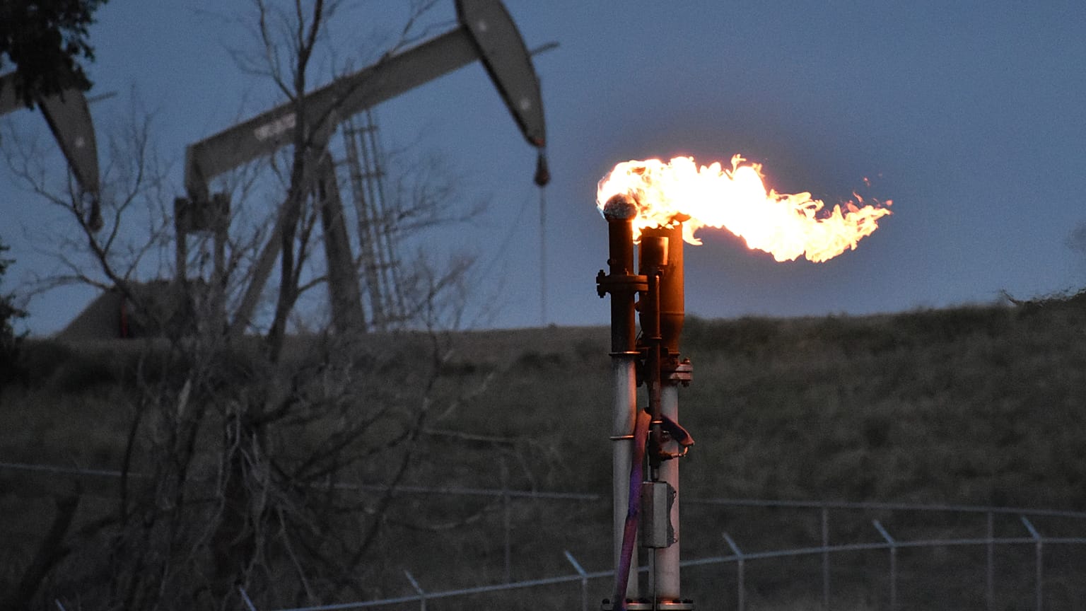 A flare to burn methane from oil production is seen on a well pad near Watford City, North Dakota, Aug. 26, 2021. 