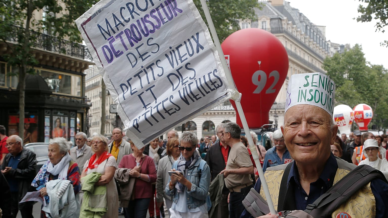 A retired man holds a placard which reads "Macron robs the money of the old men and women" during a rally in Paris, France, Thursday June 14, 2018. 