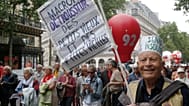 A retired man holds a placard which reads "Macron robs the money of the old men and women" during a rally in Paris, France, Thursday June 14, 2018. 