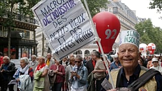 A retired man holds a placard which reads "Macron robs the money of the old men and women" during a rally in Paris, France, Thursday June 14, 2018. 
