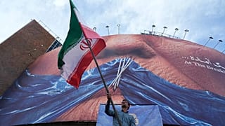 A man waves an Iranian flag for a pro-government campaign in Tehran, 6 May, 2026