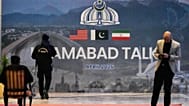 يمر حارس أمن بجوار لوحة إعلانية تتعلق بالمحادثات الأمريكية الإيرانية، خارج مركز إعلامي أُقيم لتغطية الاجتماع الرسمي بين الولايات المتحدة وإيران، في إسلام أباد بباكستان