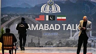يمر حارس أمن بجوار لوحة إعلانية تتعلق بالمحادثات الأمريكية الإيرانية، خارج مركز إعلامي أُقيم لتغطية الاجتماع الرسمي بين الولايات المتحدة وإيران، في إسلام أباد بباكستان
