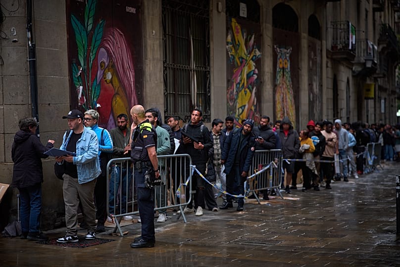 Migrants queue outside Barcelona City Hall to obtain paperwork needed to apply for Spain's immigration amnesty, 29 April, 2026