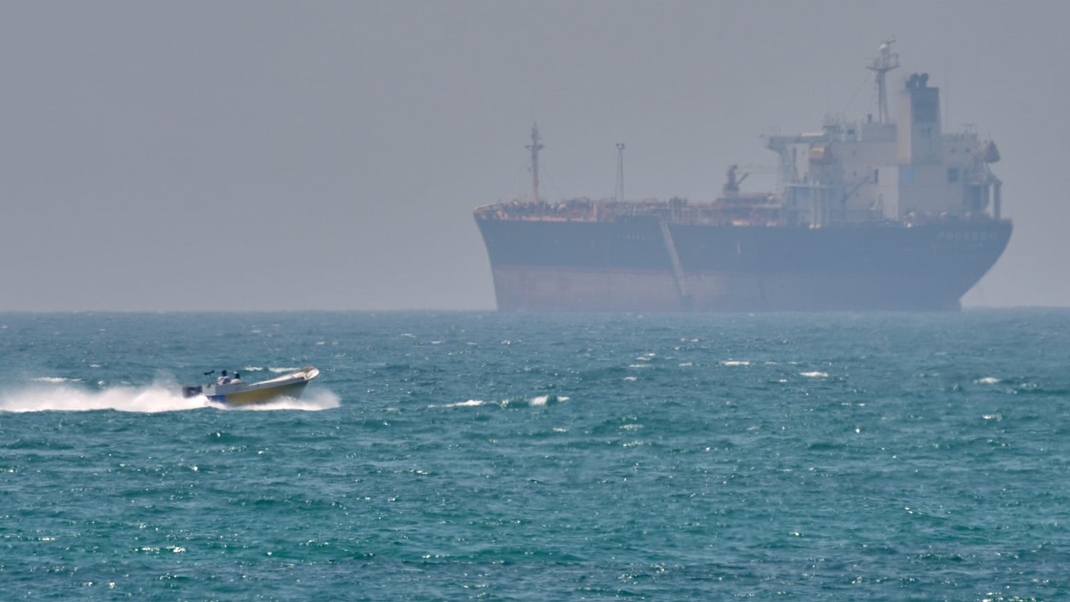  A boat sails past a tanker anchored on the Strait of Hormuz off the coast Qeshm island, Iran, April 18, 2026.