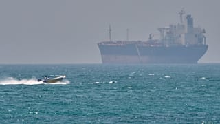  A boat sails past a tanker anchored on the Strait of Hormuz off the coast Qeshm island, Iran, April 18, 2026.