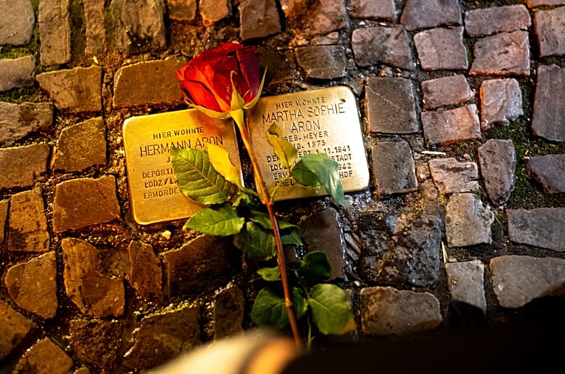 A rose is placed near a fresh polished so-called 'Stolpersteine' in Berlin, 8 November, 2023