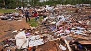 Des personnes marchent parmi les débris à Gene's Mobile Home Supply, un parc de maisons mobiles à Bogue Chitto, dans le Mississippi, jeudi 7 mai 2026,