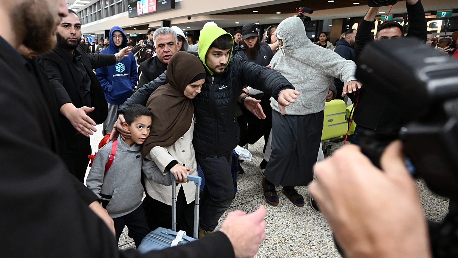 A group of supporters surround a woman with alleged ties to the Islamic State as she arrives with a child at Melbourne Airport, in Melbourne, Australia, Thursday, May 7, 2026