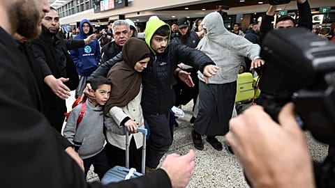 A group of supporters surround a woman with alleged ties to the Islamic State as she arrives with a child at Melbourne Airport, in Melbourne, Australia, Thursday, May 7, 2026