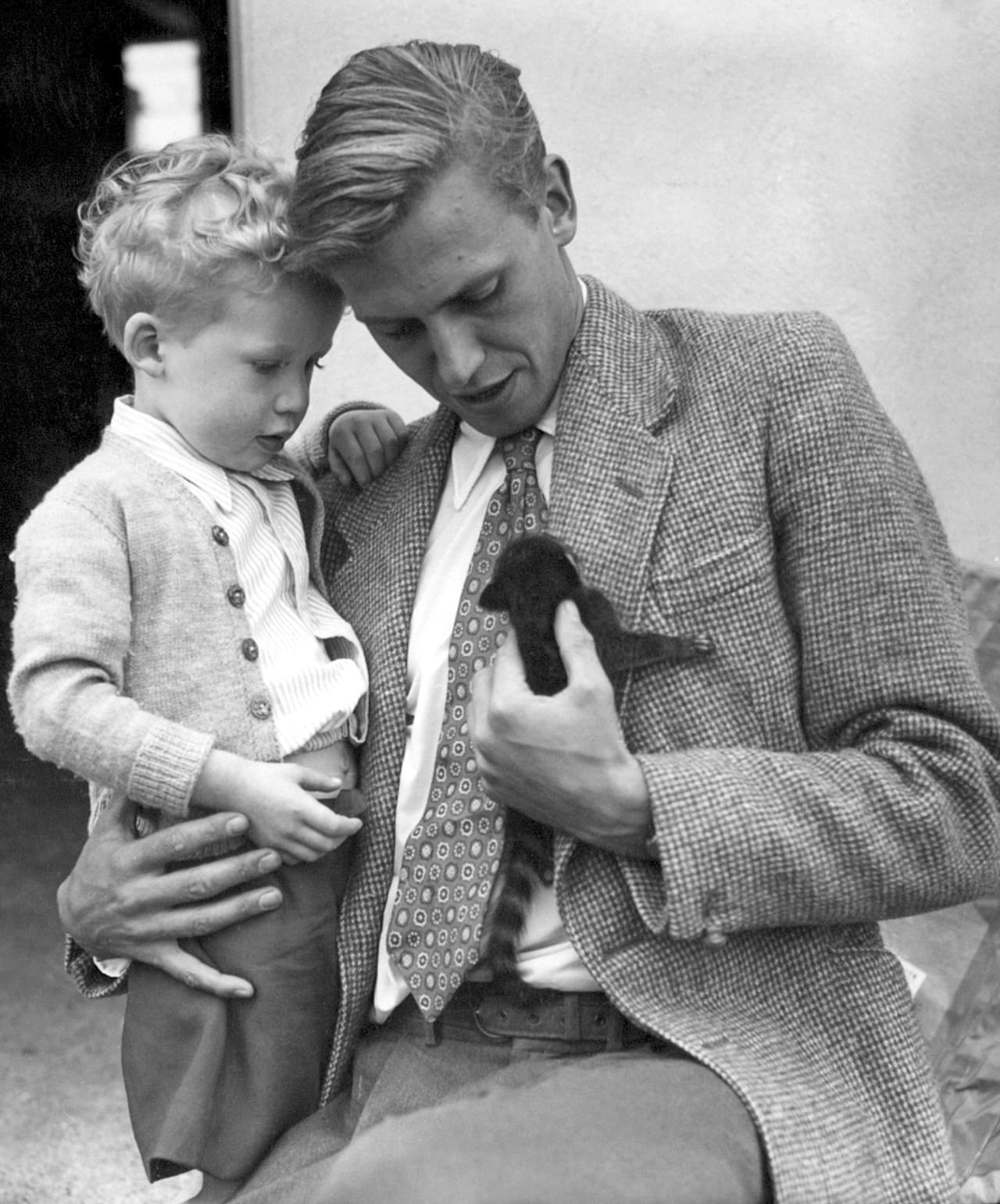 David Attenborough tiene in braccio il figlio Robert mentre osserva un coatimundi, 3 giugno 1955.