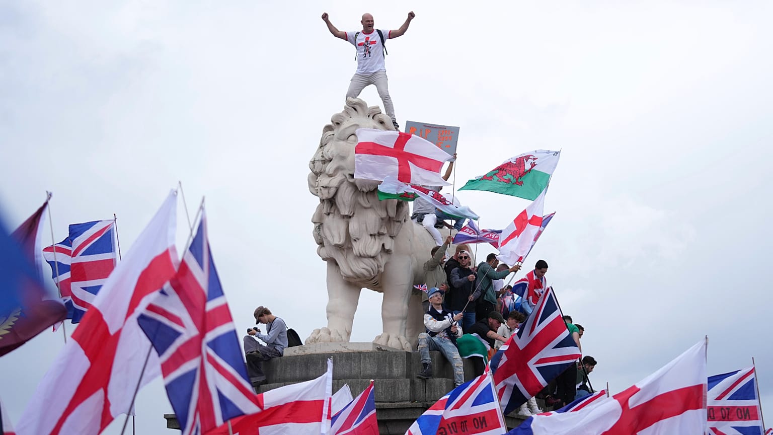 Demonstrator stands on head of lion on the side of the Westminster Bridge, during a Tommy Robinson-led Unite the Kingdom march and rally in London, 13 September 2025.