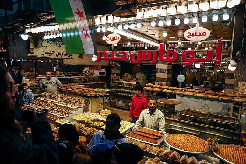 FILE: Vendors display traditional pickles and sweets as residents shop in the old city of Damascus, 1 March 2025