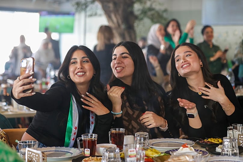 FILE: A Syrian woman with a scarf in colours of the Syrian opposition flag takes a selfie with her friends as they celebrate in a restaurant in Damascus, 17 December 2024