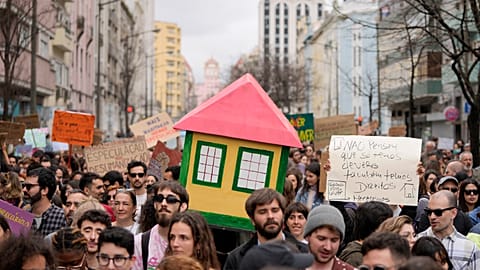 Protestors carry a mock house, during a demonstration to demand solutions for Portugal's housing crisis, in Lisbon, Saturday, April 1, 2023. 