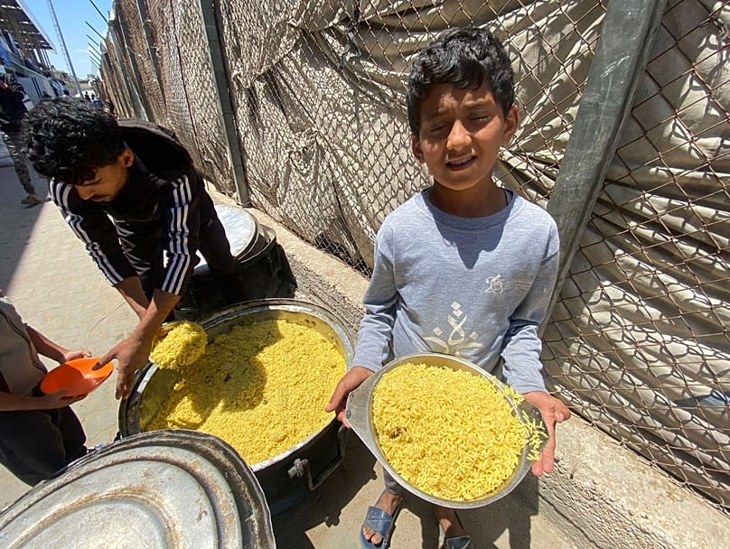 طفلان يحصلان على بعض الأرز من مطبخ خيري في وسط قطاع غزة