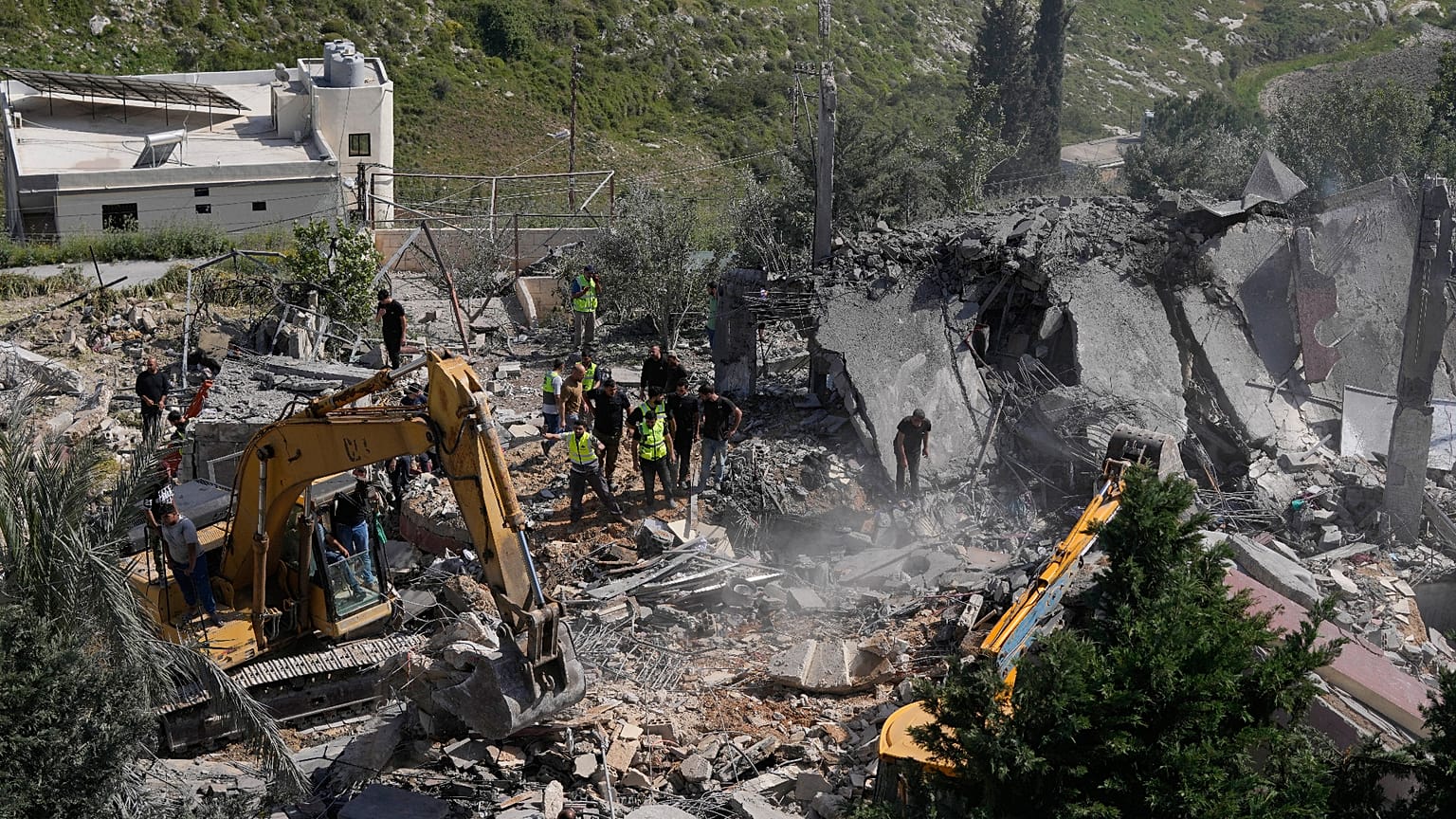 Rescue workers search for survivors using heavy machinery in the rubble of houses damaged by an Israeli airstrike in the village of Saksakieh, south Lebanon, Saturday, May 9, 