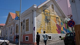 Arquivo (7.05.2026): As pessoas passam por um grafite de Amílcar Cabral num edifício na Praia, em Cabo Verde,