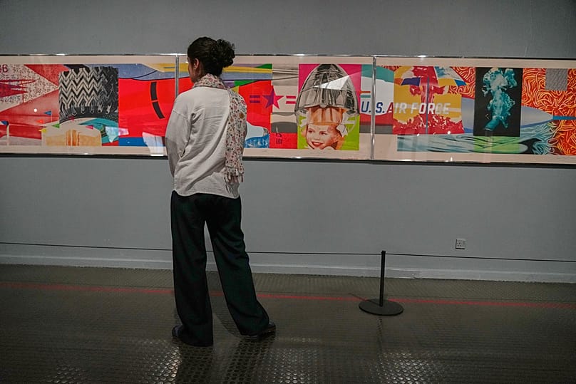 A woman looks at "F-111" an artwork of American artist James Rosenquist as she visits an exhibition called: "Art & war" displaying some artworks of American artists, Tehran.