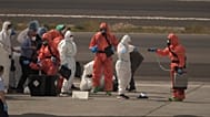 Spanyol hatóságok fertőtlenítőszerrel permetezik az utasokat, mielőtt felszállnak a gépre, miután elhagyták a hantavírussal sújtott MV Hondius hajót Tene-ben.