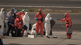 Passengers are sprayed with disinfectant by Spanish government officials before boarding a plane after disembarking from the hantavirus-stricken cruise ship MV Hondius at Tene