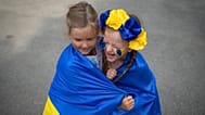   FILE: Ukrainian refugee children play wrapped in Ukraine's flag, Bucharest, Romania, , Aug. 24, 2022. 