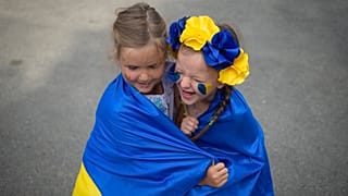   FILE: Bambini ucraini rifugiati giocano avvolti nella bandiera dell'Ucraina, Bucarest, Romania, 24 agosto 2022. 