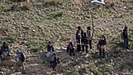 Palestinian students walk to school along a fence separating their village from a nearby Israeli settlement of Carmel, which forces them to take an alternative route nearly tw