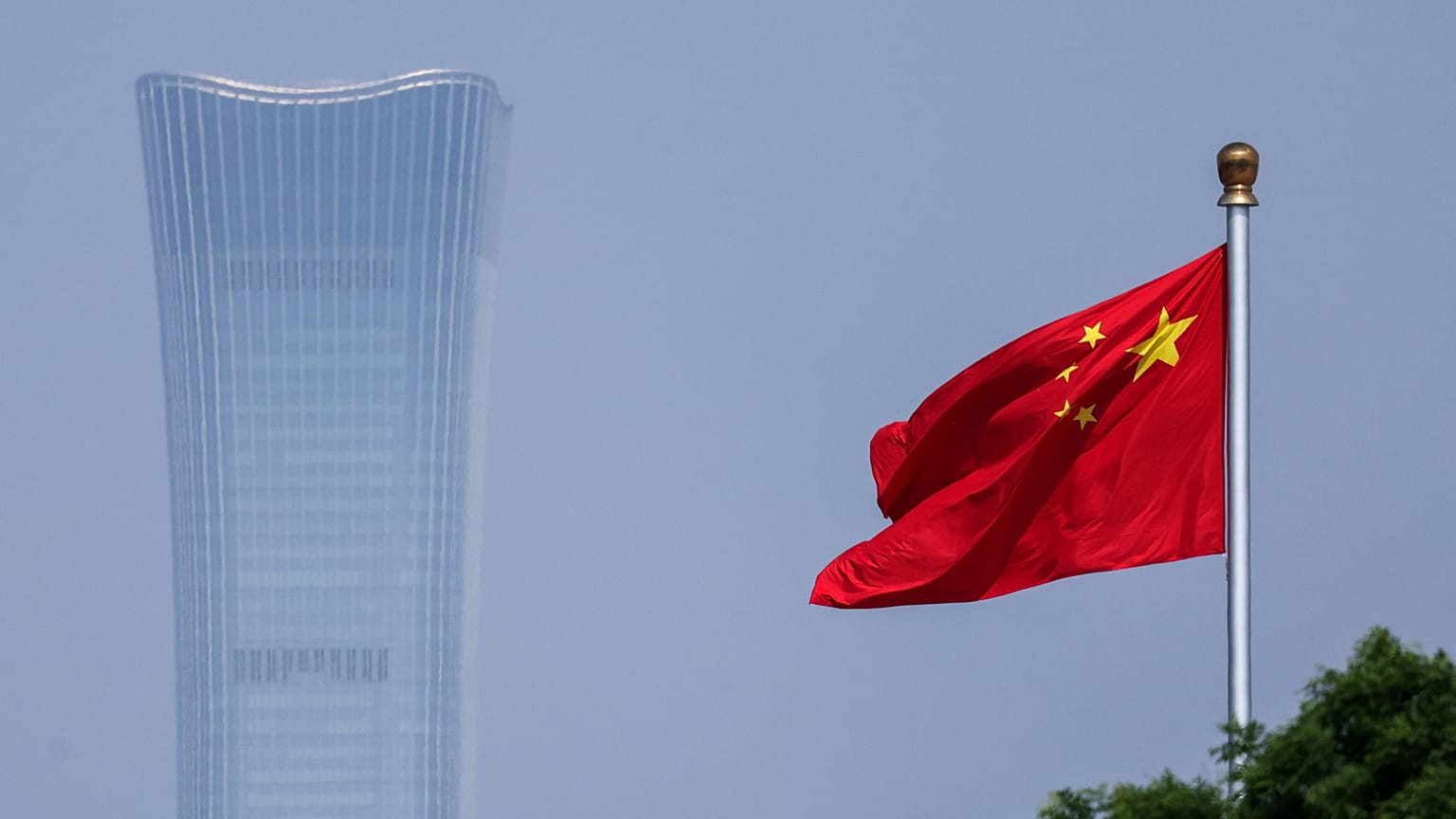 China's national flag flutters in the wind next to the CITIC tower 