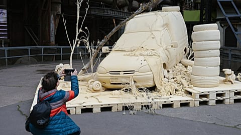 A woman takes a photo of "Les Silence des Departs" by Tomas Lacque at the Urban Art Biennale in Germany, 6 May 2026
