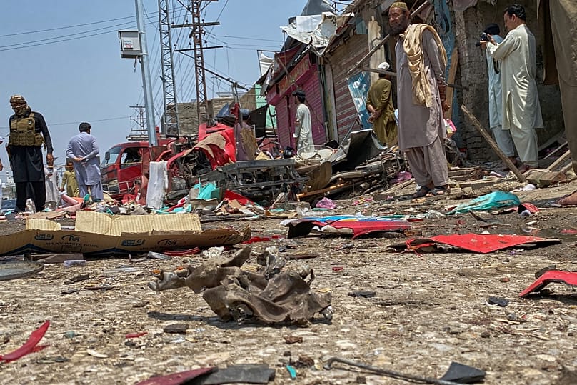 Plainclothes police officers and local residents examine damage at the site of a bomb explosion at a market in Sarai Norag, 12 May, 2026