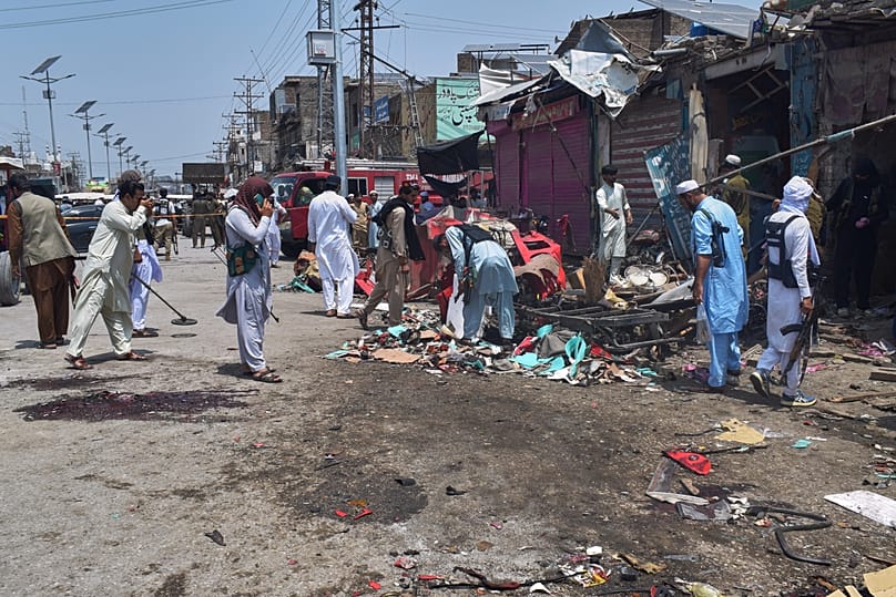 Plainclothes police officers and local residents examine damage at the site of a bomb explosion at a market in Sarai Norag, 12 May, 2026